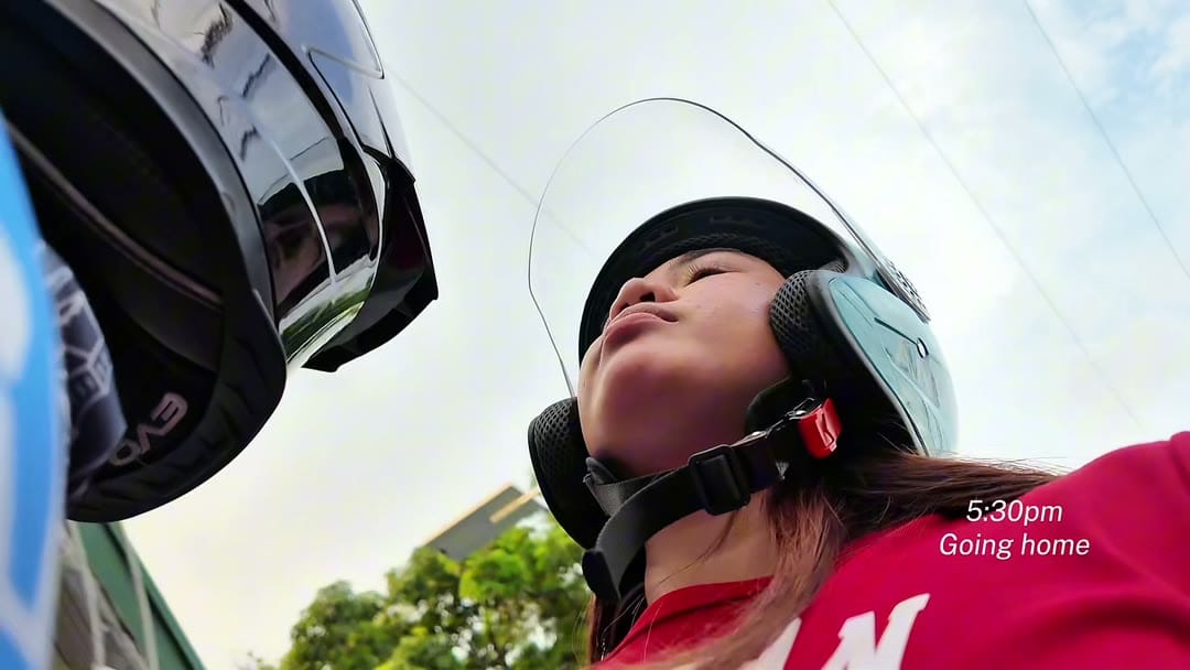 Aliyha in a helmet on a motorbike, looking up at the sky on the ride home