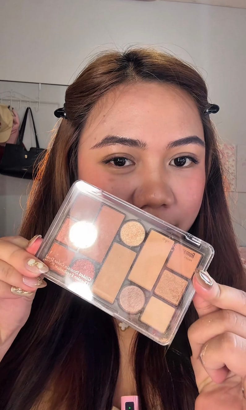 Aliyha holding an eyeshadow palette up to the camera