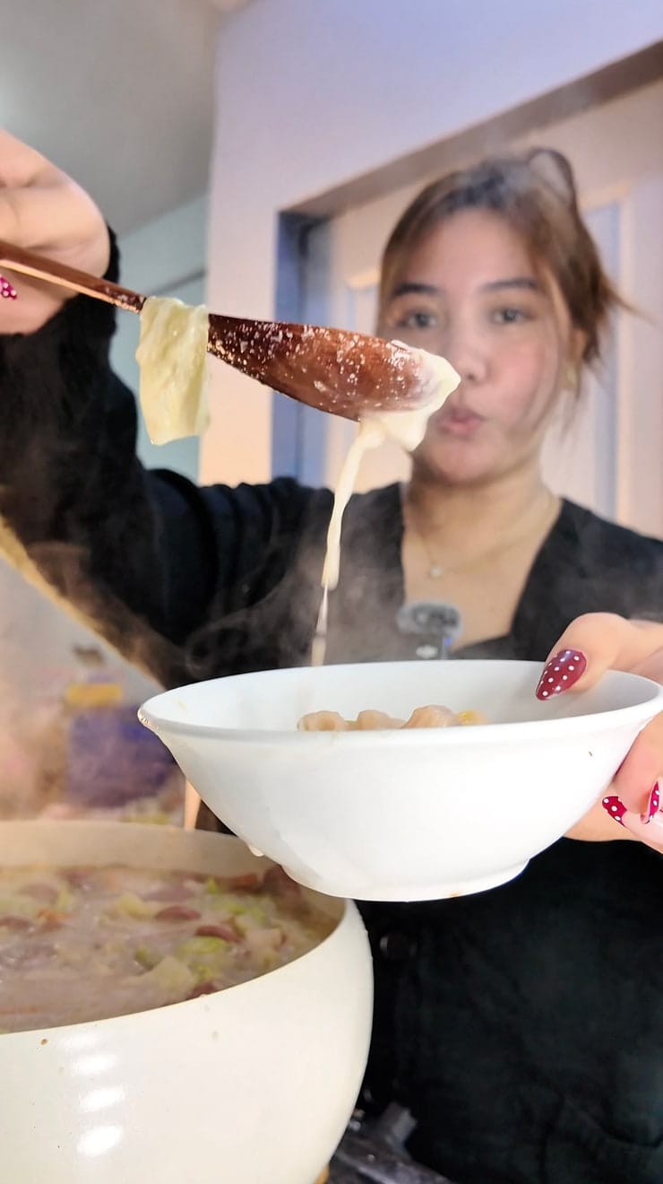 Aliyha ladling soup from a large pot in her kitchen